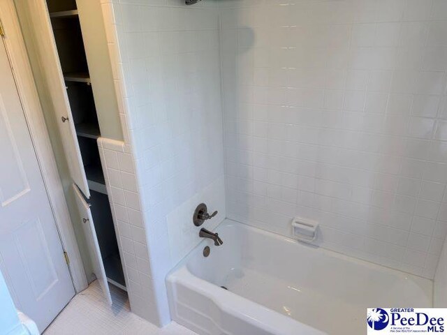 bathroom featuring tile patterned flooring, tiled shower / bath, and tile walls