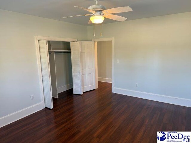 unfurnished bedroom featuring ceiling fan, dark hardwood / wood-style flooring, and a closet