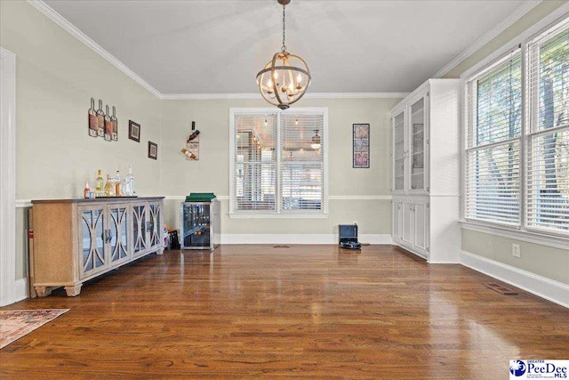 unfurnished dining area featuring visible vents, an inviting chandelier, wood finished floors, and ornamental molding