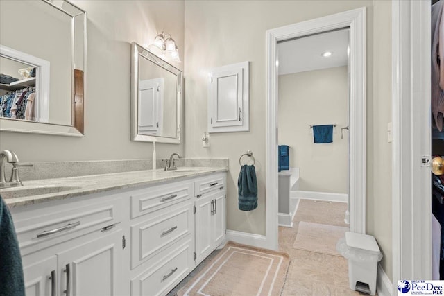 bathroom featuring double vanity, tile patterned floors, baseboards, and a sink