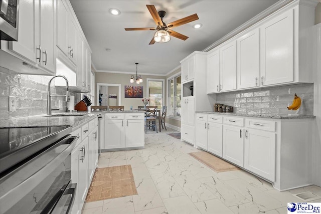 kitchen featuring marble finish floor, a peninsula, white cabinetry, and crown molding