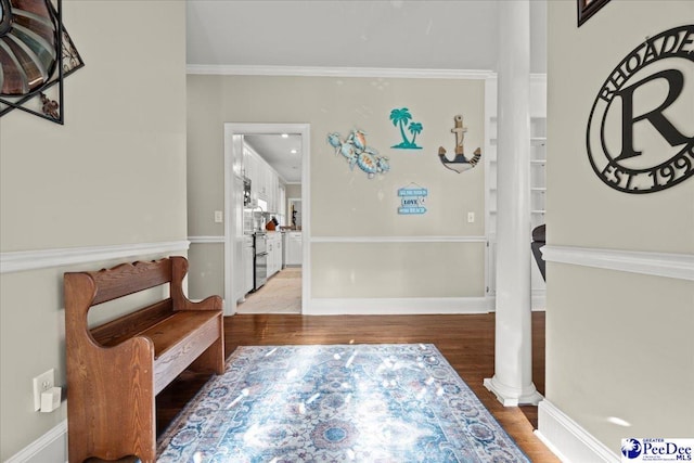 foyer featuring light wood finished floors, ornate columns, baseboards, and ornamental molding