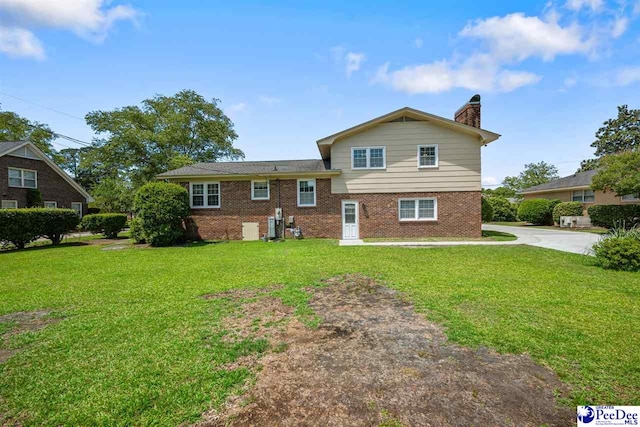 908 Clarendon Ave, Florence, SC 29505 - rear view of house featuring brick siding, a yard, a chimney, and central AC unit