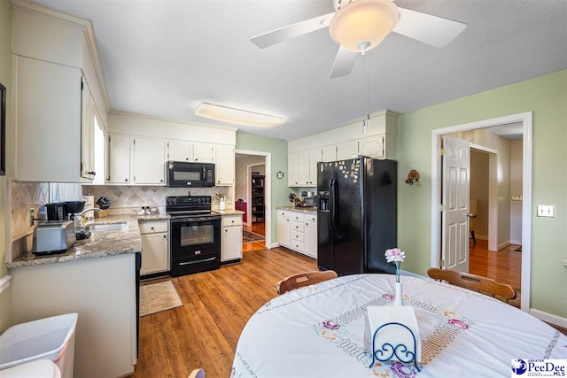 908 Clarendon Ave, Florence, SC 29505 - kitchen with black appliances, light wood-style flooring, tasteful backsplash, and white cabinetry