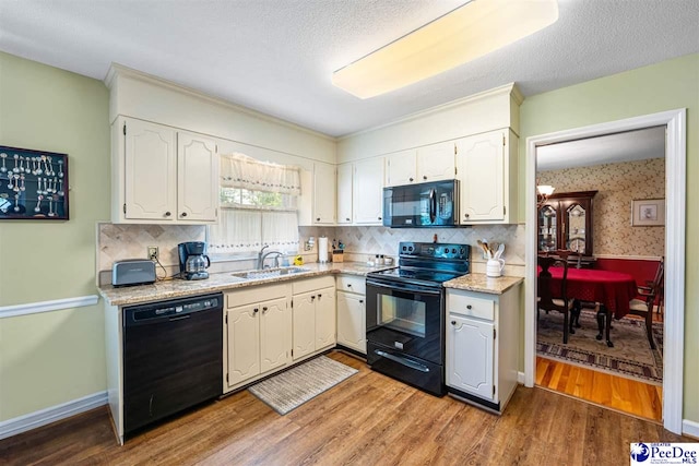 908 Clarendon Ave, Florence, SC 29505 - kitchen featuring black appliances, a sink, light wood-style floors, tasteful backsplash, and white cabinetry