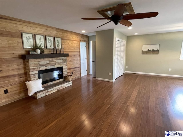 1429 E Home Ave, Hartsville, SC 29550 - unfurnished living room featuring a ceiling fan, wooden walls, a stone fireplace, baseboards, and dark wood finished floors