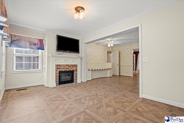 unfurnished living room with a wainscoted wall, visible vents, ornamental molding, a brick fireplace, and wallpapered walls