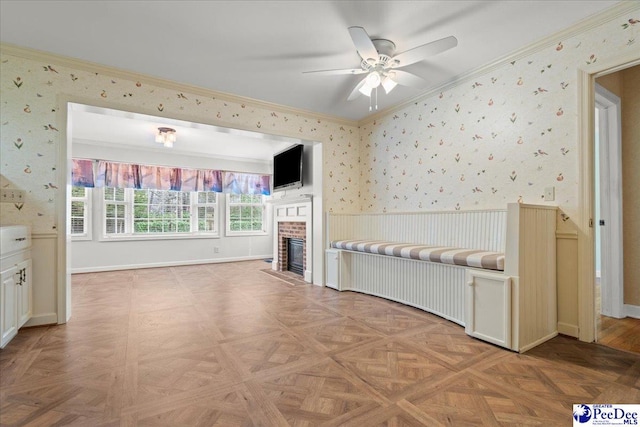 unfurnished bedroom featuring wallpapered walls, baseboards, a wainscoted wall, crown molding, and a brick fireplace