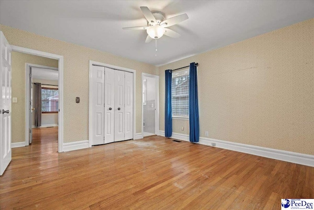 unfurnished bedroom featuring light wood finished floors, baseboards, visible vents, ceiling fan, and a closet