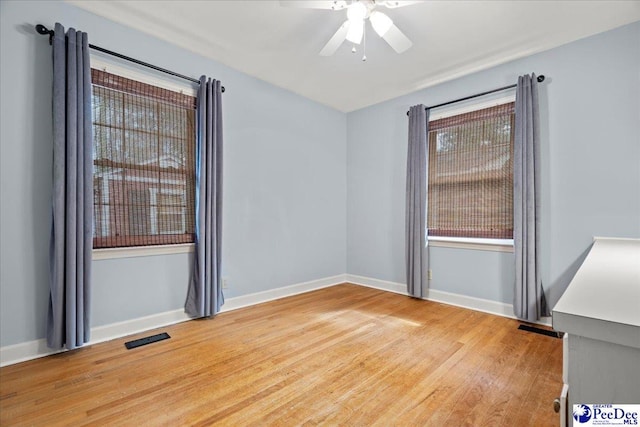 unfurnished room featuring a ceiling fan, light wood-style flooring, visible vents, and baseboards