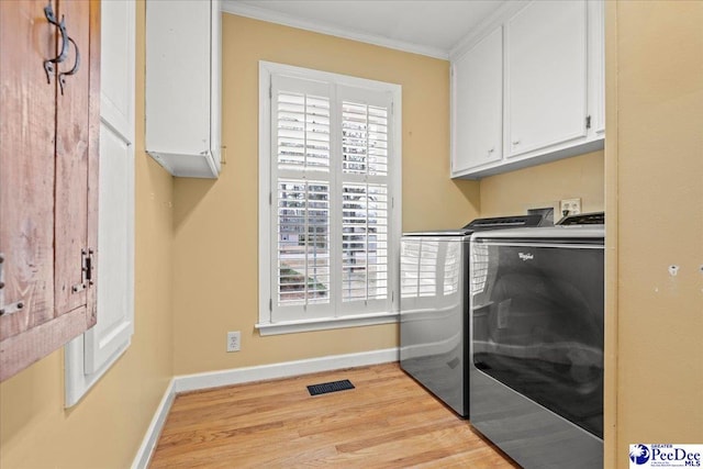 washroom featuring visible vents, ornamental molding, light wood-type flooring, cabinet space, and washer and clothes dryer