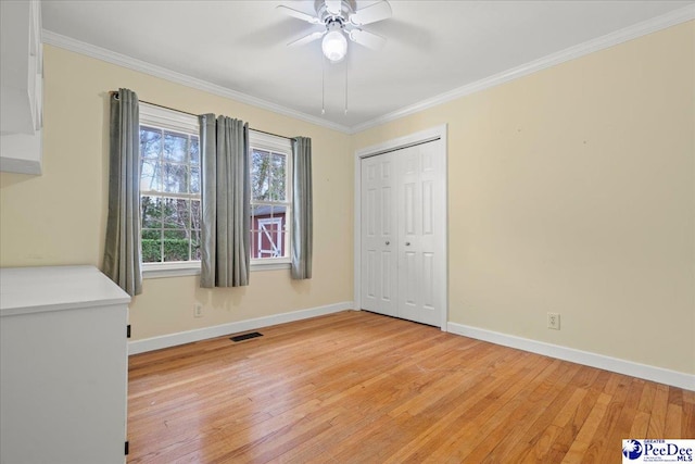 unfurnished bedroom with baseboards, light wood-style flooring, visible vents, and crown molding