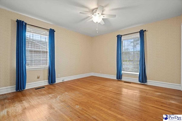 unfurnished room featuring visible vents, ceiling fan, baseboards, and wood finished floors