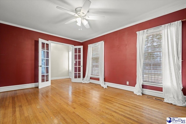 empty room with ornamental molding, french doors, visible vents, and wood finished floors