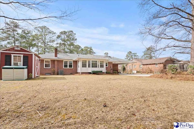 view of front of home with an outbuilding, brick siding, and a chimney