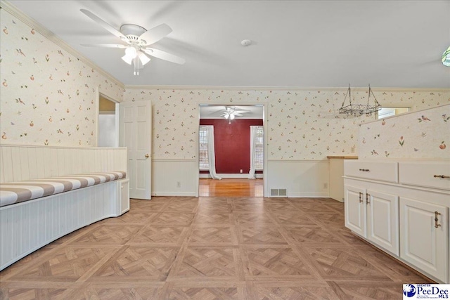 unfurnished bedroom with ornamental molding, wainscoting, visible vents, and wallpapered walls