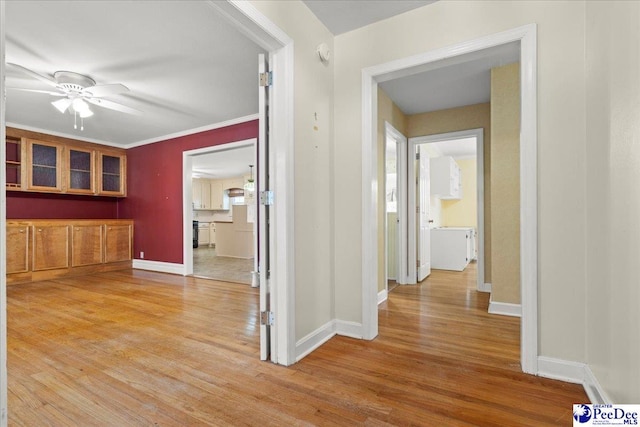 hallway featuring crown molding, light wood finished floors, and baseboards