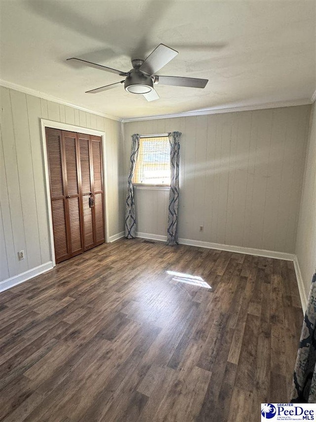 unfurnished bedroom featuring crown molding, dark wood-type flooring, and ceiling fan