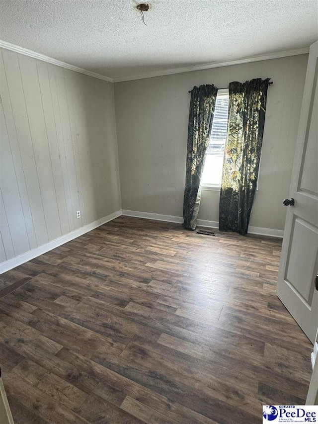 spare room featuring crown molding, dark hardwood / wood-style flooring, and a textured ceiling