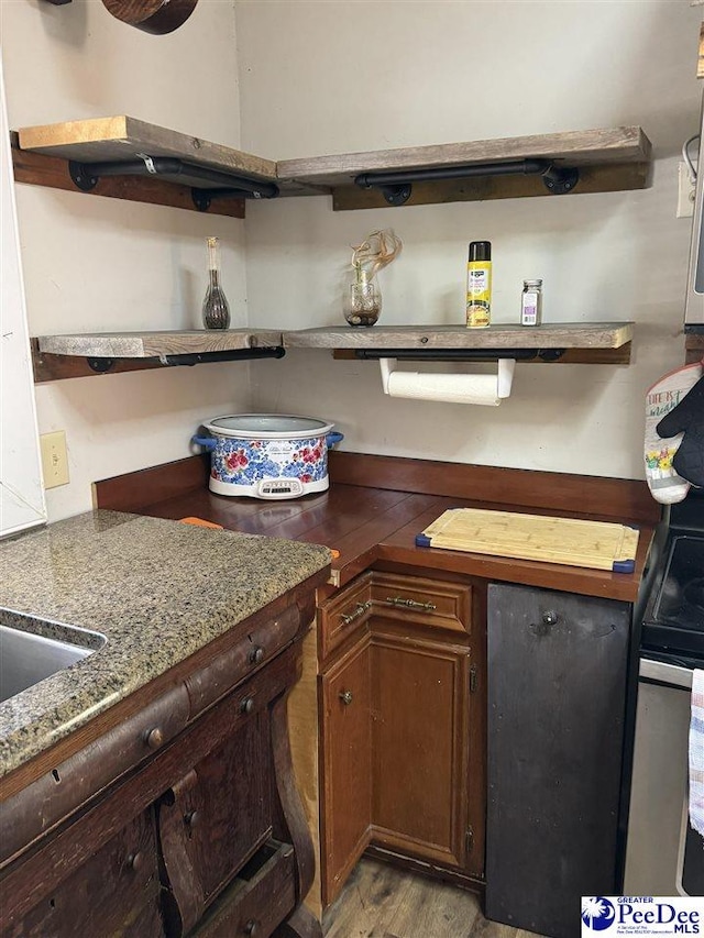 kitchen featuring stainless steel electric range, light hardwood / wood-style floors, and stone countertops