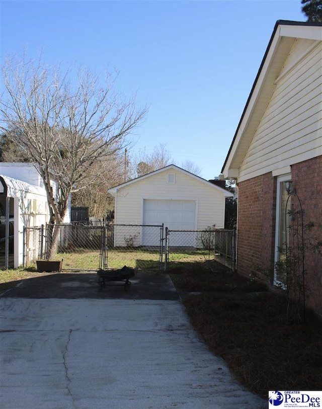 view of property exterior with a garage, driveway, a gate, an outdoor structure, and brick siding