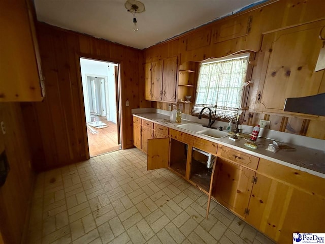 kitchen with wooden walls, a sink, light countertops, brick patterned floor, and open shelves