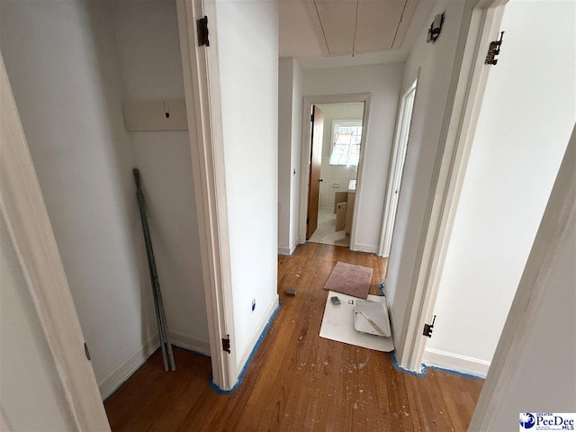 hall with attic access, baseboards, and wood finished floors