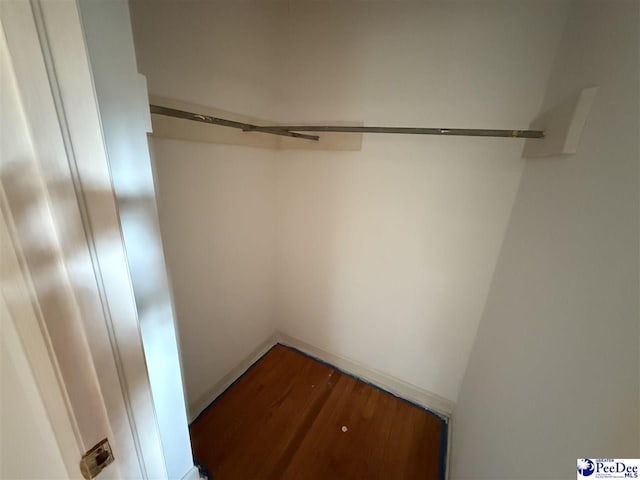 walk in closet with wood finished floors