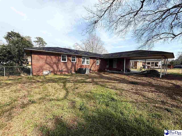 back of house with brick siding, crawl space, central AC, fence, and a carport