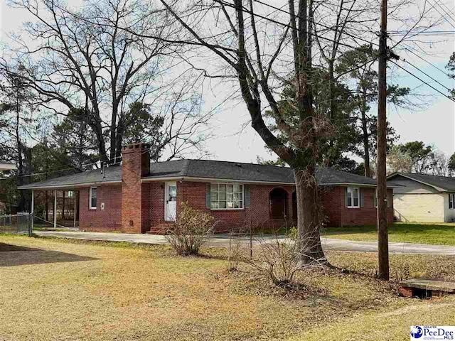 ranch-style home featuring a front yard, brick siding, and a chimney