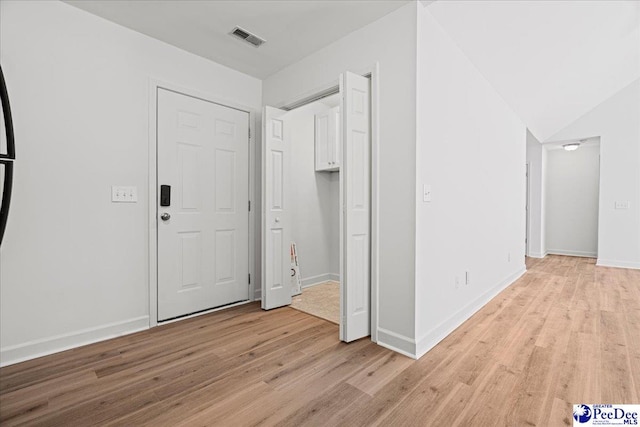 interior space featuring light wood-style floors, visible vents, vaulted ceiling, and baseboards