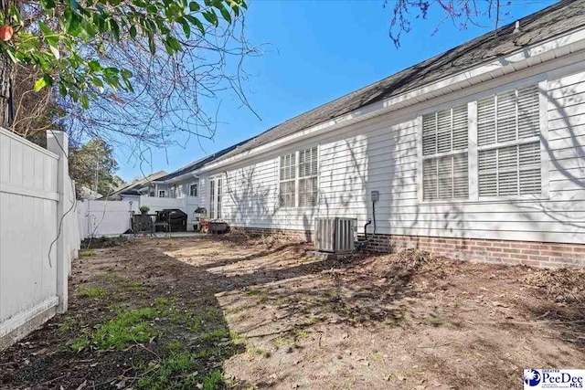 view of side of property featuring a fenced backyard and central AC