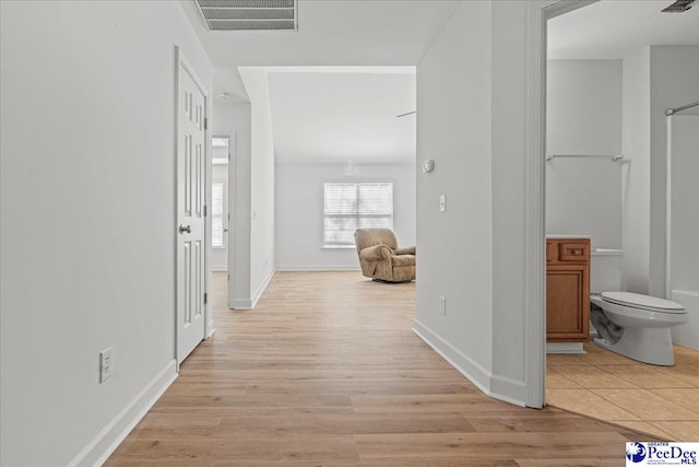 hallway featuring light wood-type flooring, baseboards, and visible vents