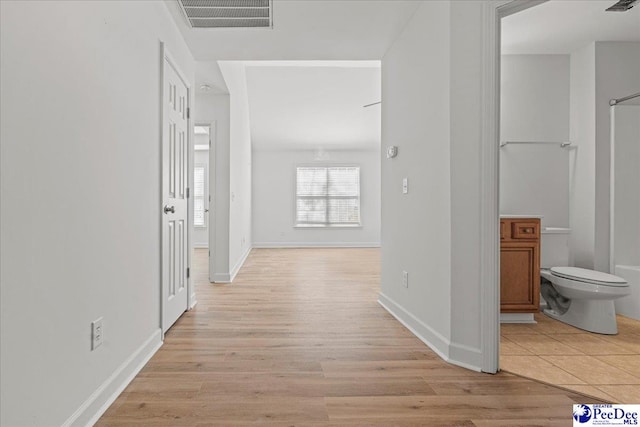 hallway featuring light wood-type flooring, visible vents, and baseboards