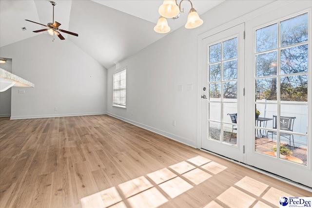 unfurnished living room featuring visible vents, baseboards, light wood-style flooring, high vaulted ceiling, and ceiling fan with notable chandelier