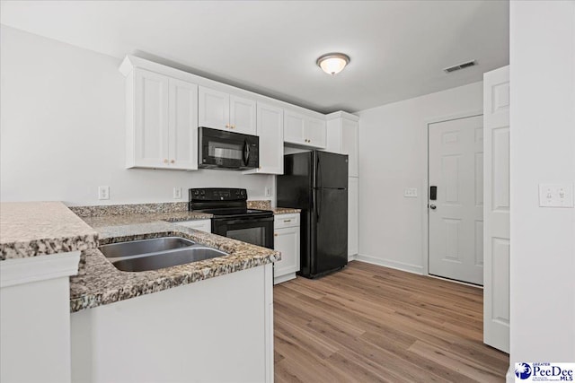 kitchen with black appliances, visible vents, and white cabinets