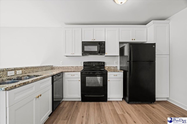 kitchen with black appliances, stone countertops, and white cabinetry