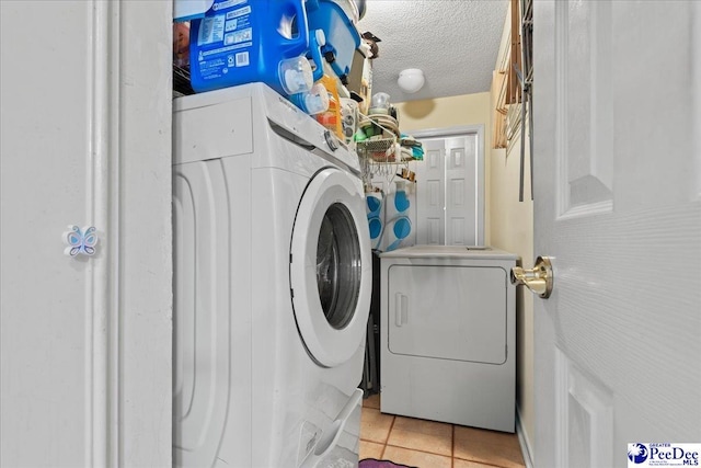 laundry room featuring independent washer and dryer, light tile patterned flooring, laundry area, and a textured ceiling