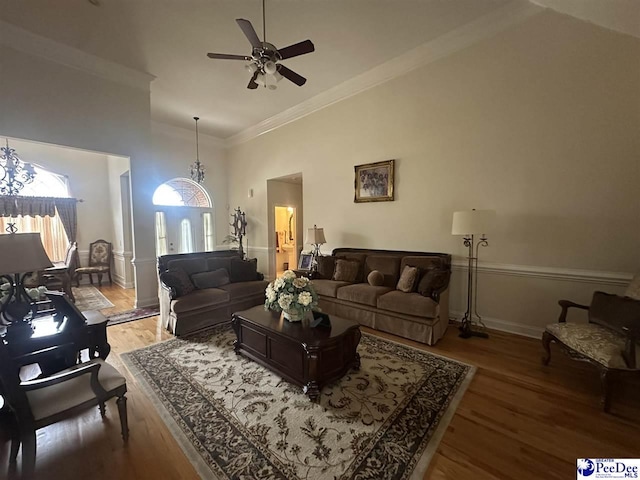 living room featuring a ceiling fan, high vaulted ceiling, crown molding, and wood finished floors