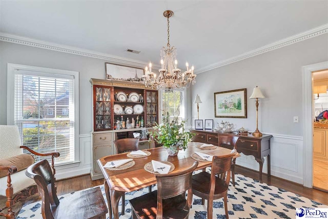 dining room with crown molding, wood-type flooring, and a chandelier