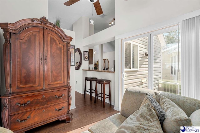 living room with ceiling fan, dark hardwood / wood-style floors, and vaulted ceiling