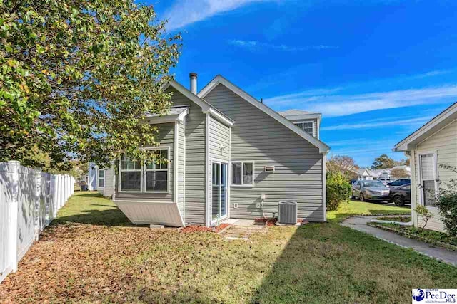 rear view of property featuring cooling unit and a lawn