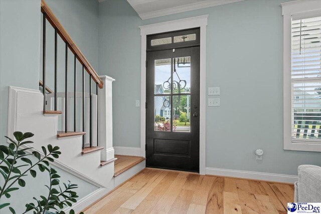 foyer with wood finished floors, stairway, crown molding, and baseboards