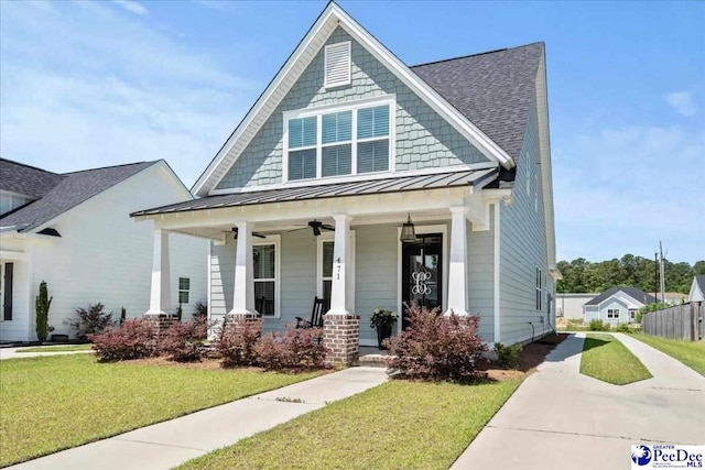 view of front facade featuring a porch, a front lawn, a standing seam roof, a ceiling fan, and a shingled roof