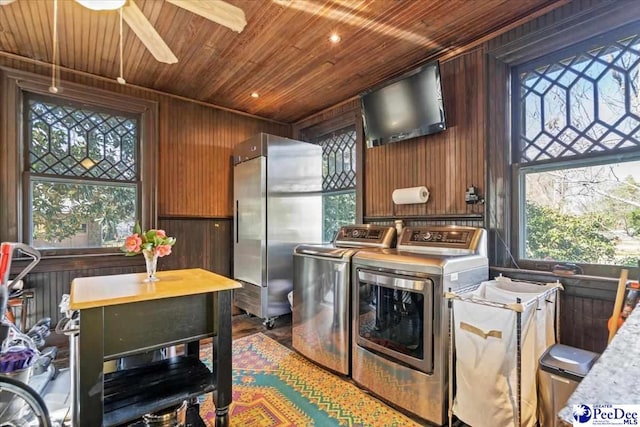 kitchen featuring ceiling fan, wooden ceiling, washer and dryer, and wood walls