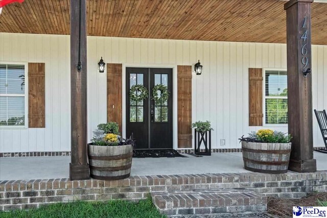 view of exterior entry featuring french doors and covered porch