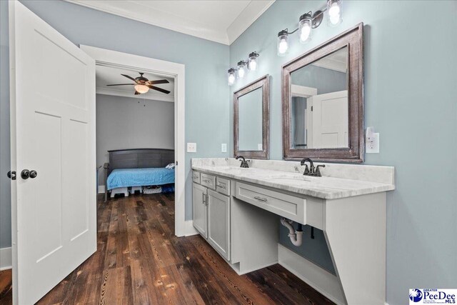 ensuite bathroom featuring crown molding, ceiling fan, a sink, and hardwood / wood-style floors