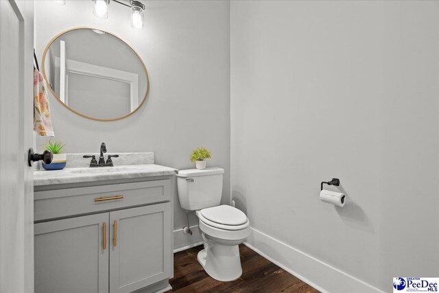bathroom featuring baseboards, wood finished floors, toilet, and vanity