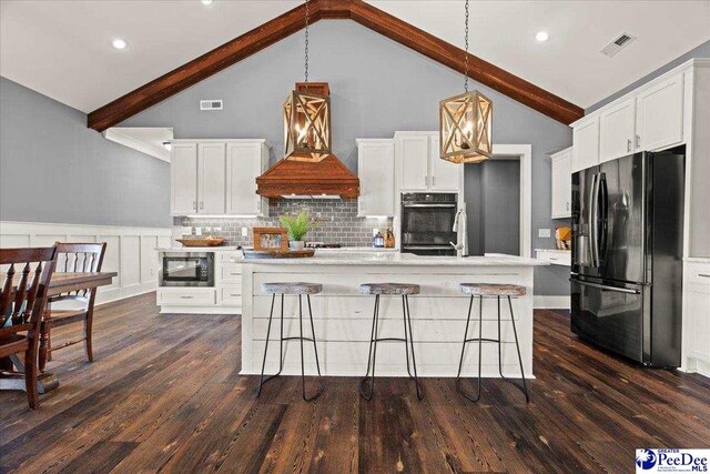 kitchen with visible vents, premium range hood, lofted ceiling with beams, black appliances, and white cabinetry