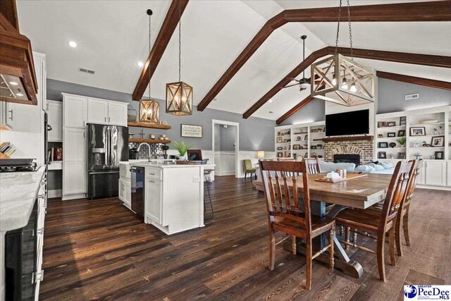 dining room featuring an inviting chandelier, dark wood-style flooring, a brick fireplace, beamed ceiling, and high vaulted ceiling